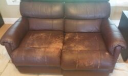 Worn brown leather loveseat before restoration